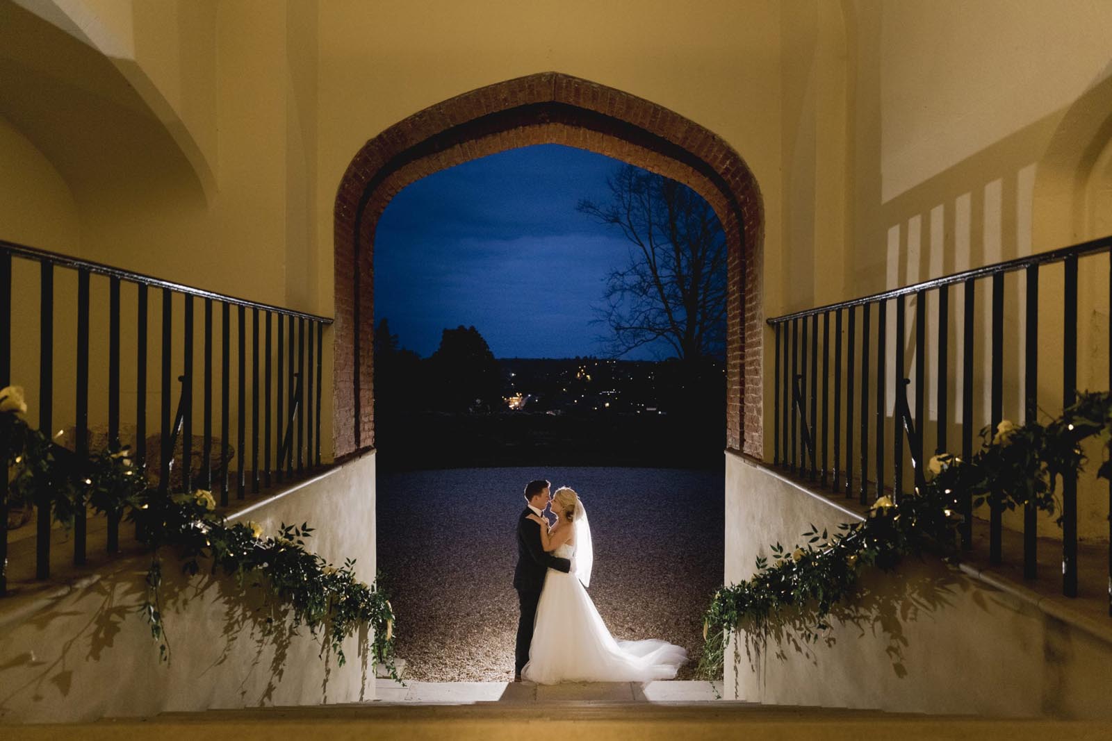 Bride and groom at the base of the steps of the entrance to Farnham Castle