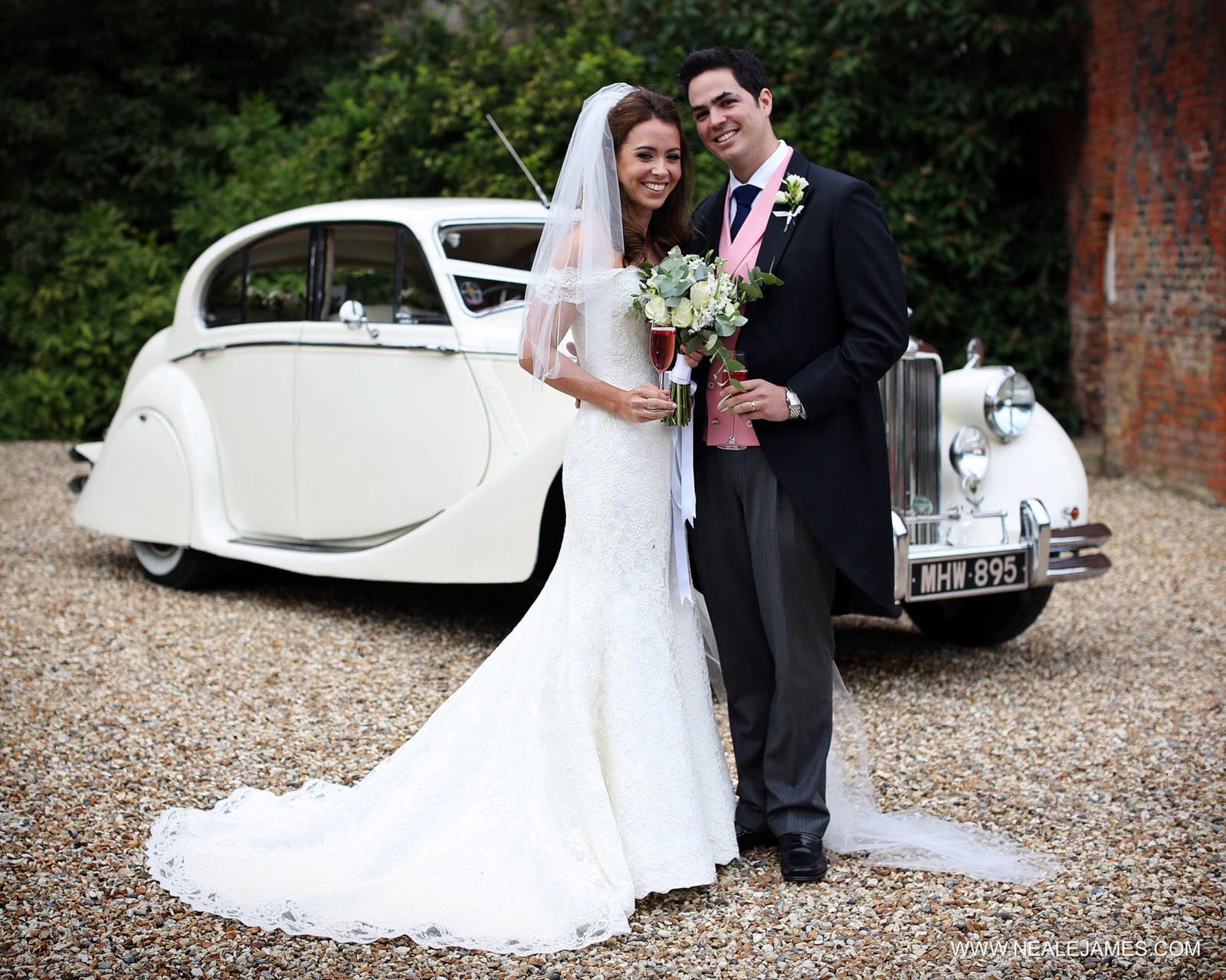 Newlyweds with their wedding car at Farnham Castle