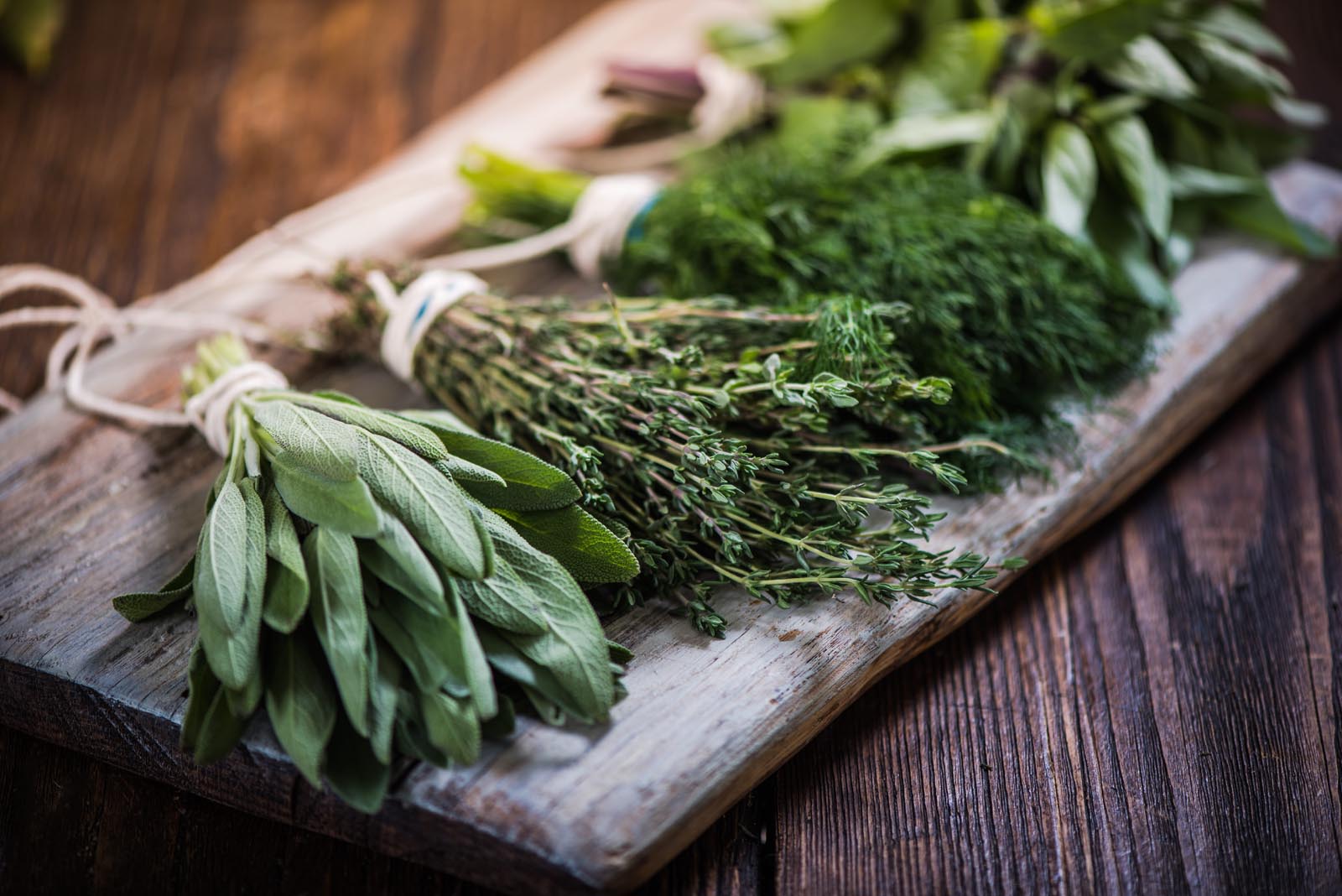 A selection of fresh herbs placed on a wooden tray