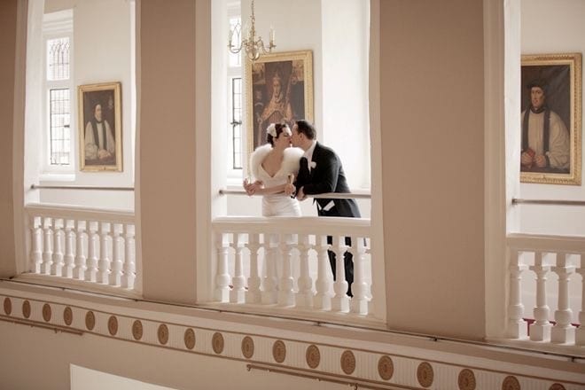 Newlyweds kissing on a balcony at Farnham Castle