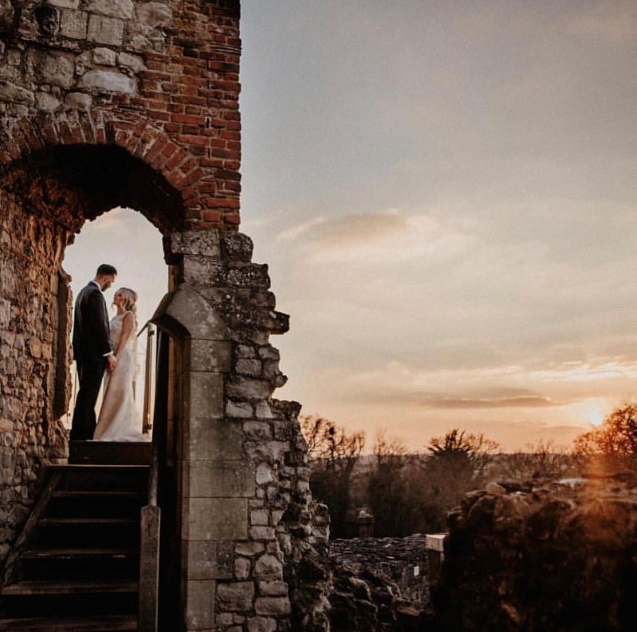 Wedding couple standing within Farnham Castle Keep at sunset